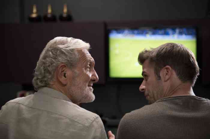 Abuelo y nieto miran juntos el partido de fútbol