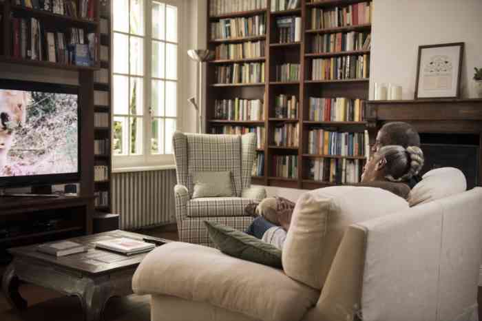 Una pareja ve la televisión escuchando el sonido con audífonos retroauriculares