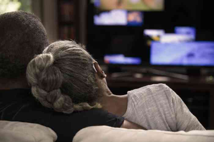 Una pareja escucha el sonido de la televisión con audífonos retroauriculares