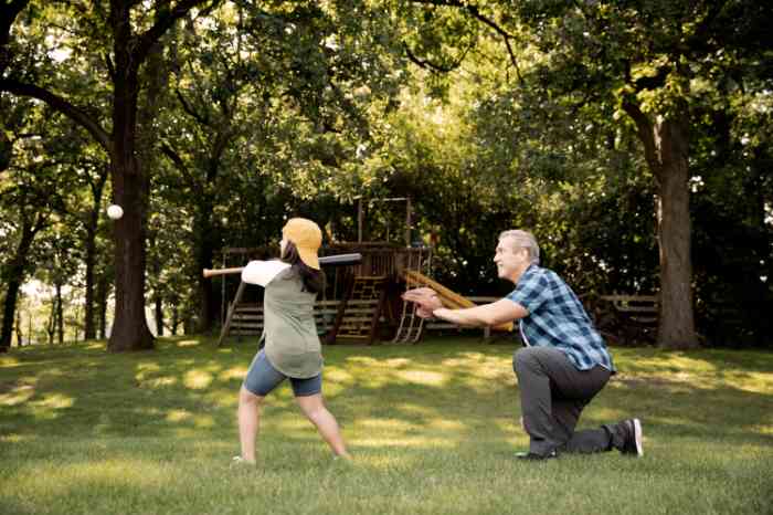 Abuelo y nieta jugando béisbol en un jardín