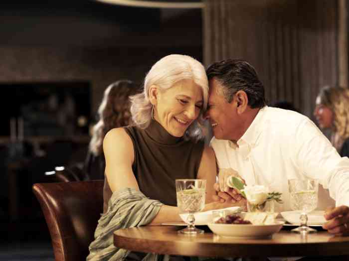 Un hombre con audífono auricular en el canal cena con su esposa en un restaurante