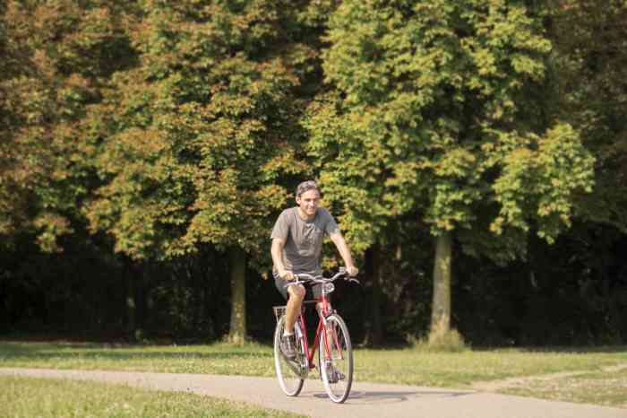 Un hombre con su bicicleta en el sendero de un parque