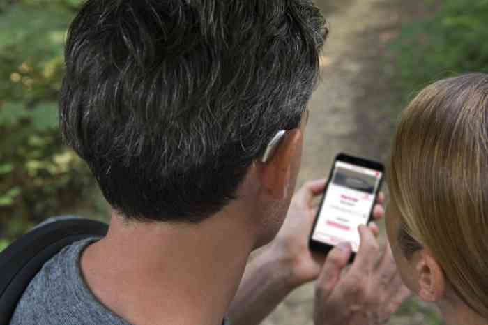Una pareja con audífono retroauricular mira la página web de Gaes en un móvil