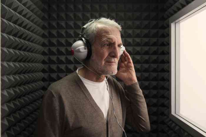 Un hombre mayor durante una prueba auditiva en una cabina insonorizada