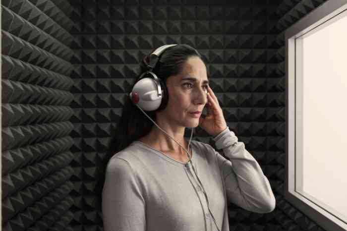 Una mujer con cascos durante una prueba auditiva en una cabina insonorizada