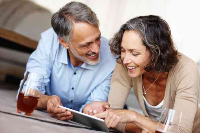 Un hombre y una mujer sonríen mirando su tablet