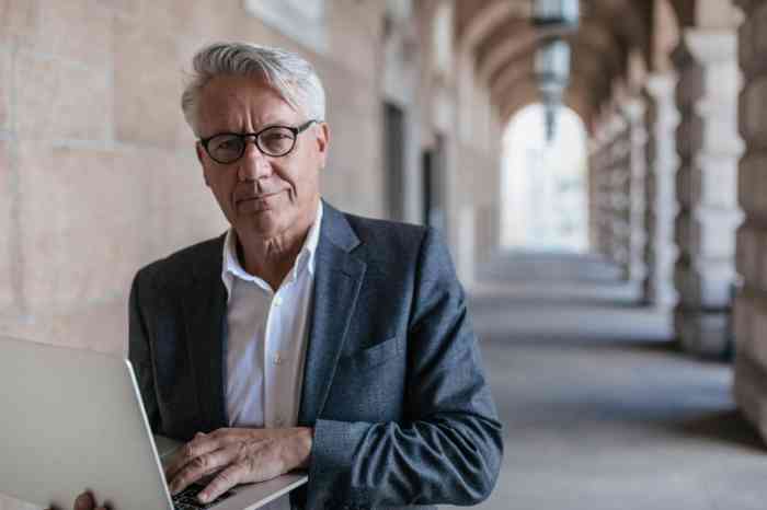 Un hombre mayor con gafas y una computadora en sus manos