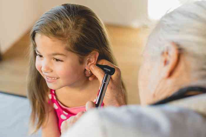 Un audioprotesista le controla el oído a una niña