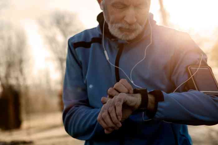 Un hombre mayor corre con sus auriculares controlando su reloj